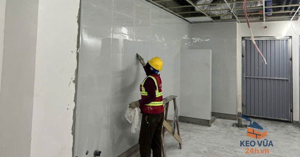 Công nhân trét keo chà ron mạch gạch ốp tường tại công trình.